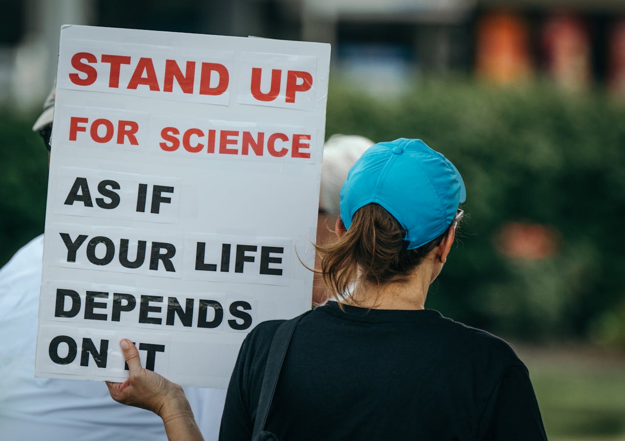 Back view of person holding a protest sign advocating for science in a public setting.