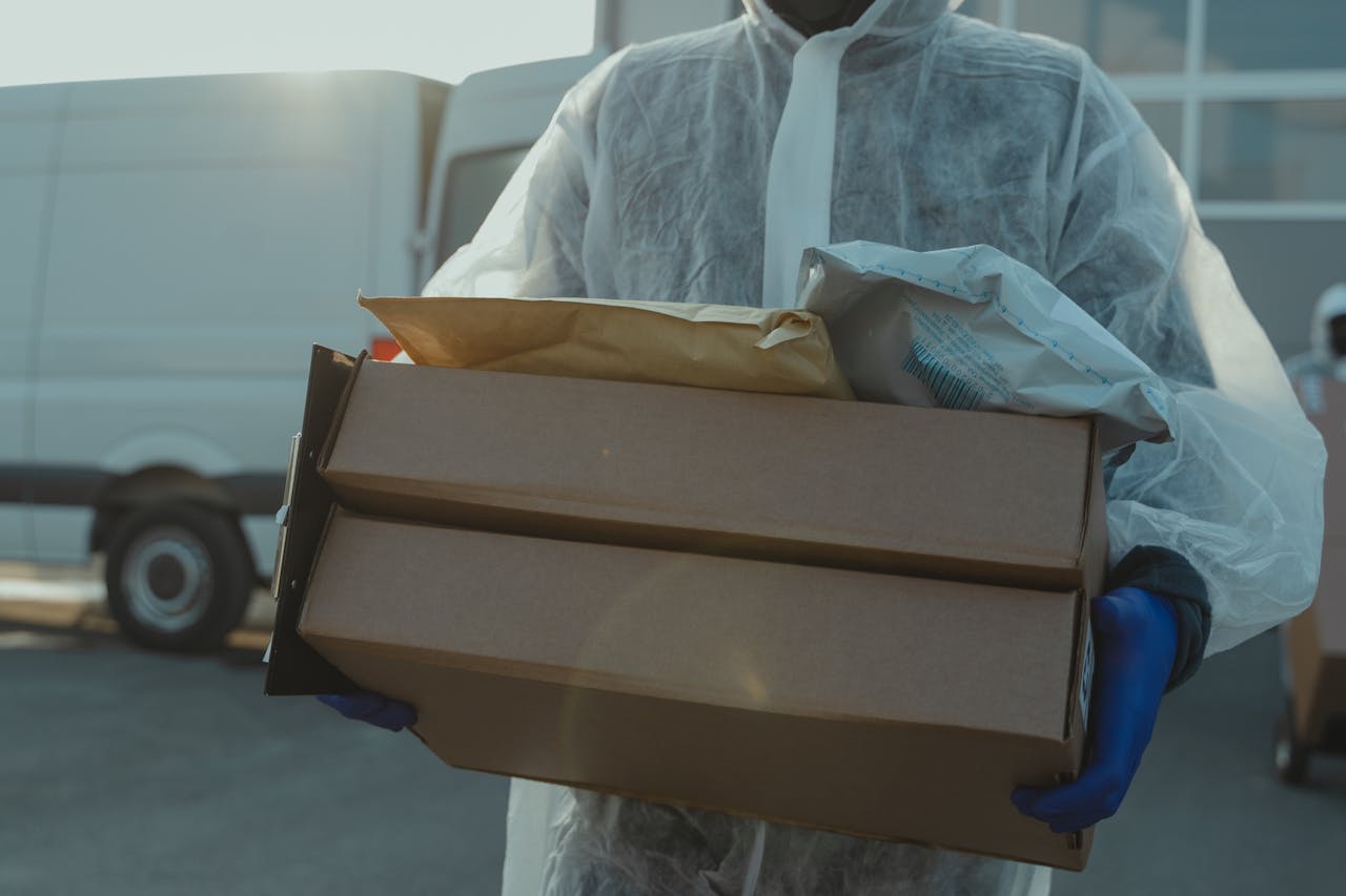A delivery person in PPE carrying packages outside during COVID-19 pandemic.