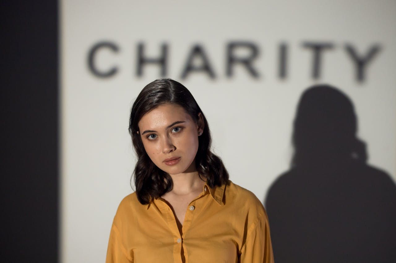 A thoughtful woman stands before a charity-themed backdrop, evoking compassion and volunteerism.